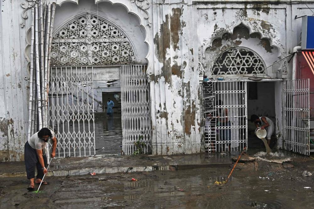 Workers clear the water from the flooded complex of a mosque after heavy monsoon rains in Karachi on August 20, 2025. (AFP)