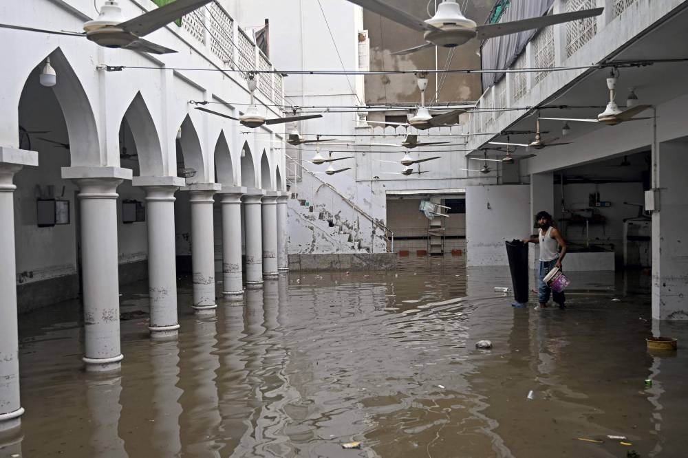 A man wades through the complex of a flooded mosque after heavy monsoon rains in Karachi on August 20, 2025. (AFP)