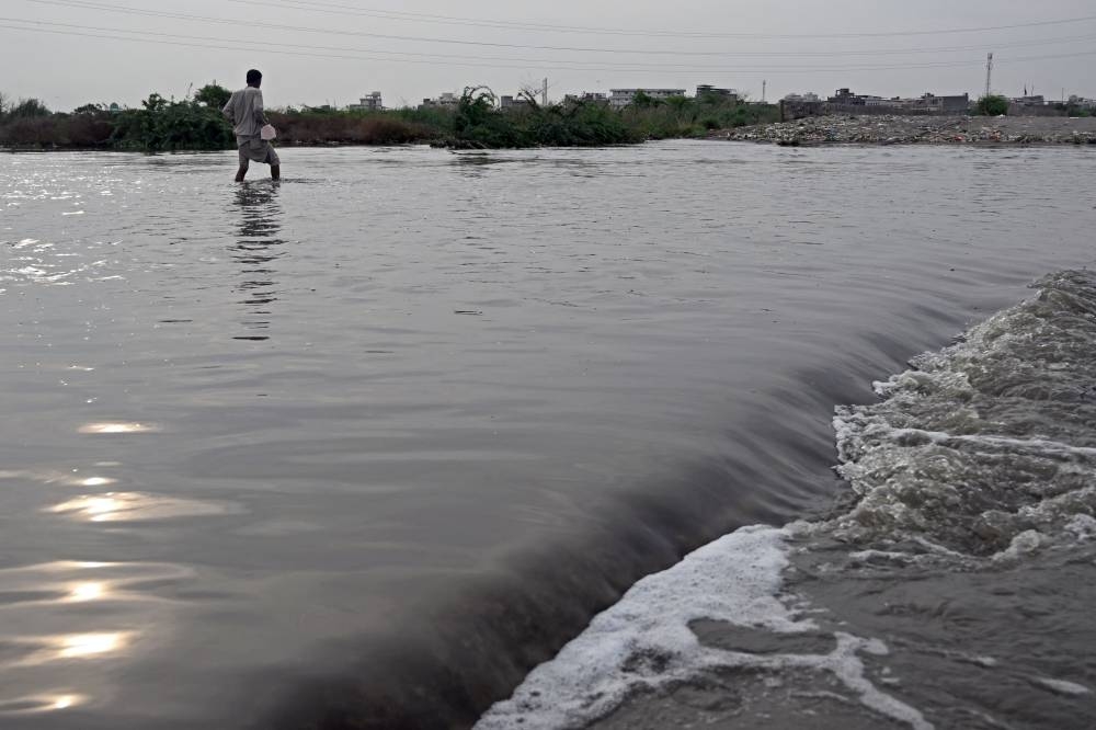 A man wades through a flooded street after heavy monsoon rains in Karachi on August 20, 2025. (AFP)