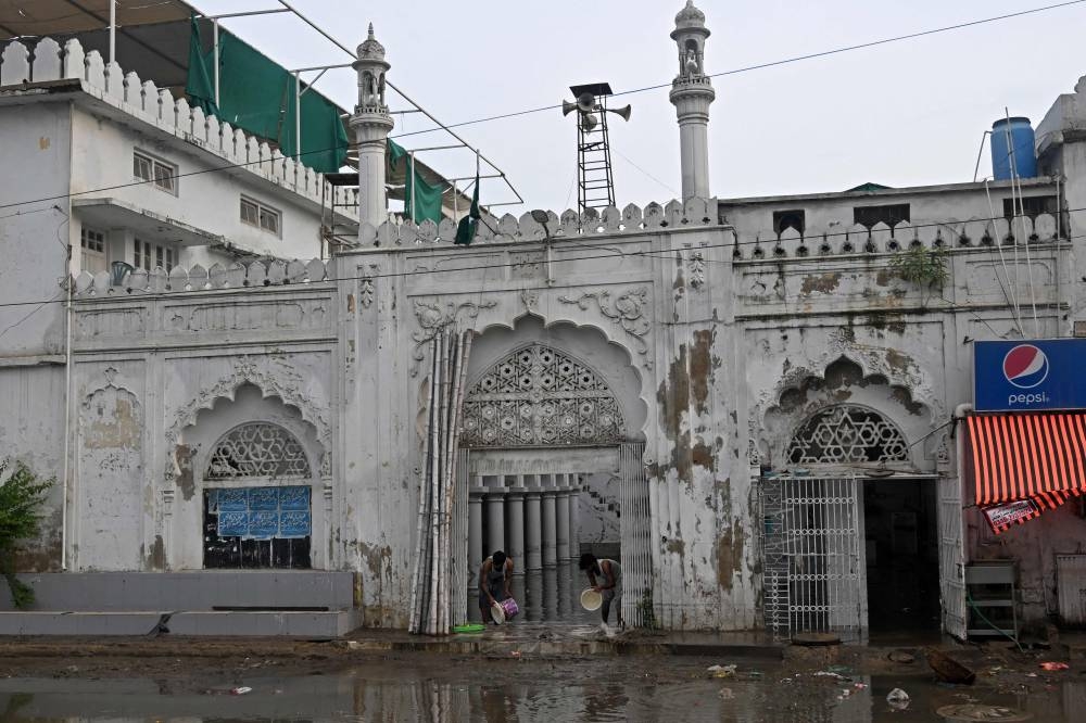 Workers clear the water from the flooded complex of a mosque after heavy monsoon rains in Karachi on August 20, 2025. (AFP)