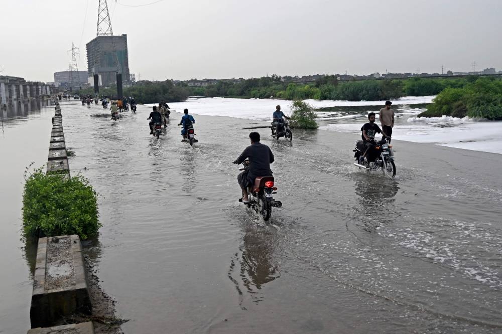 Motorists make their way through a flooded street after heavy monsoon rains in Karachi on August 20, 2025. (AFP)