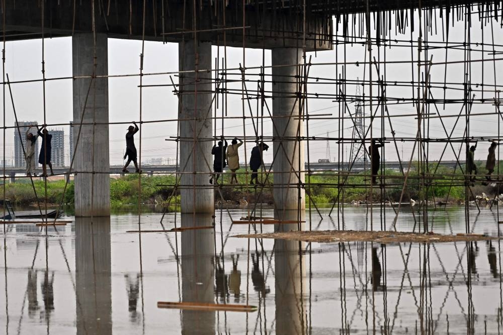Laborers work at a flooded construction site after heavy monsoon rains in Karachi on August 20, 2025. (AFP)