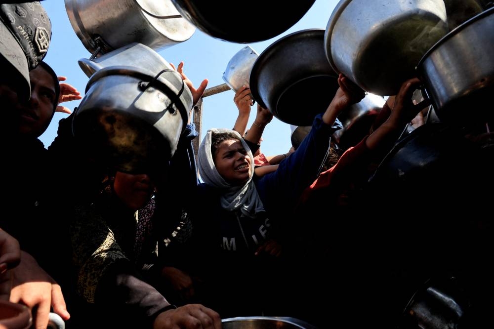 Palestinians wait to receive food from a charity kitchen, in Khan Younis, southern Gaza Strip, August 21, 2025. REUTERS