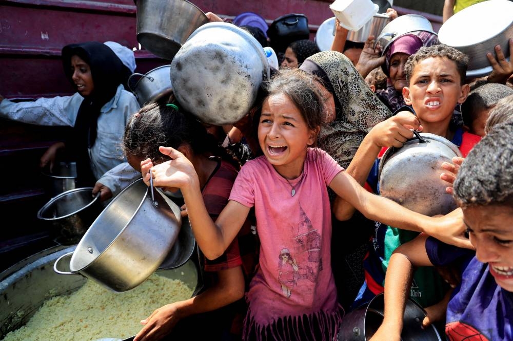 Palestinians wait to receive food from a charity kitchen, in Khan Younis, southern Gaza Strip, August 21, 2025. REUTERS