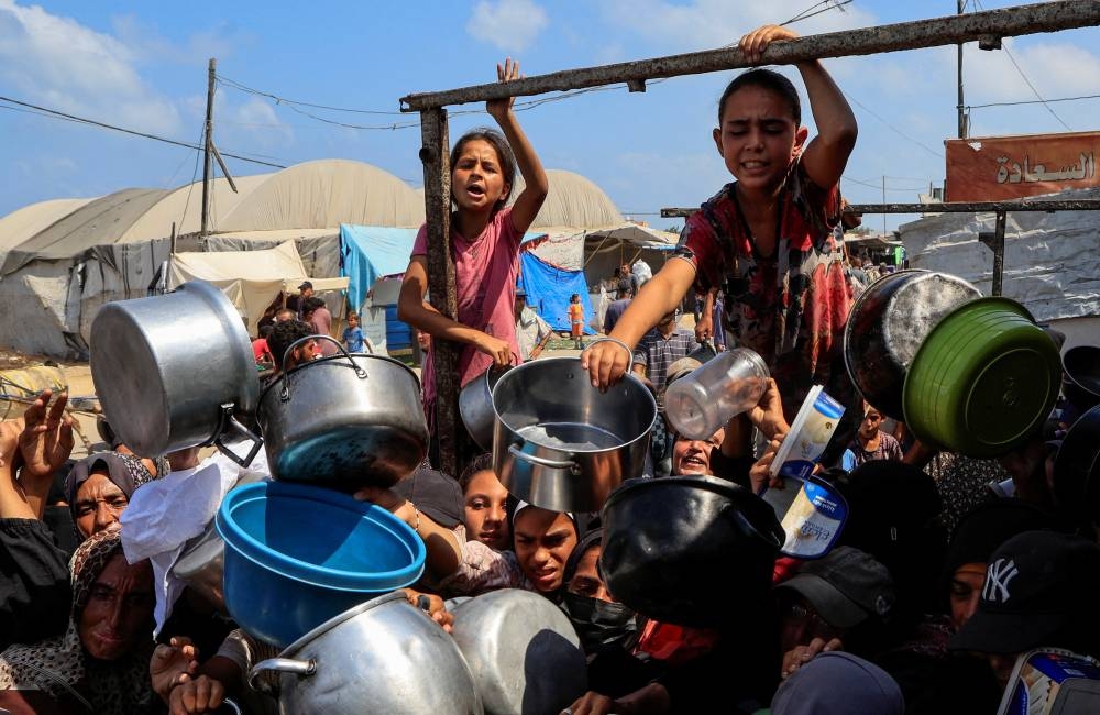 Palestinians wait to receive food from a charity kitchen, in Khan Younis, southern Gaza Strip, August 21, 2025. REUTERS