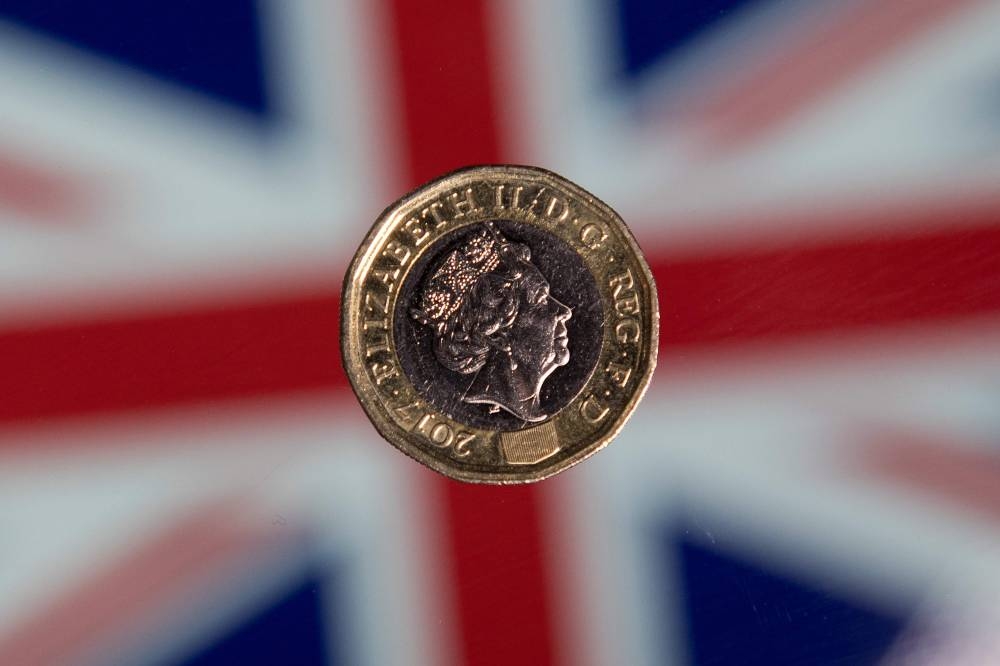 A British one pound sterling coin is arranged for a photograph in front of a Union flag in London.