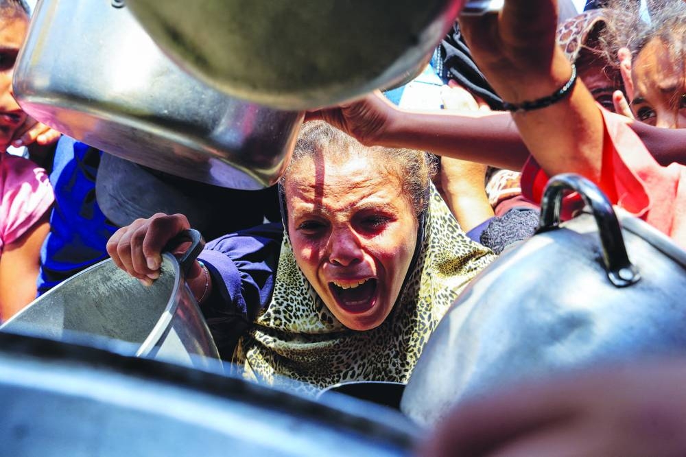 A Palestinian reacts while waiting to receive food from a charity kitchen, in Khan Younis, southern Gaza Strip, August 21, 2025. REUTERS