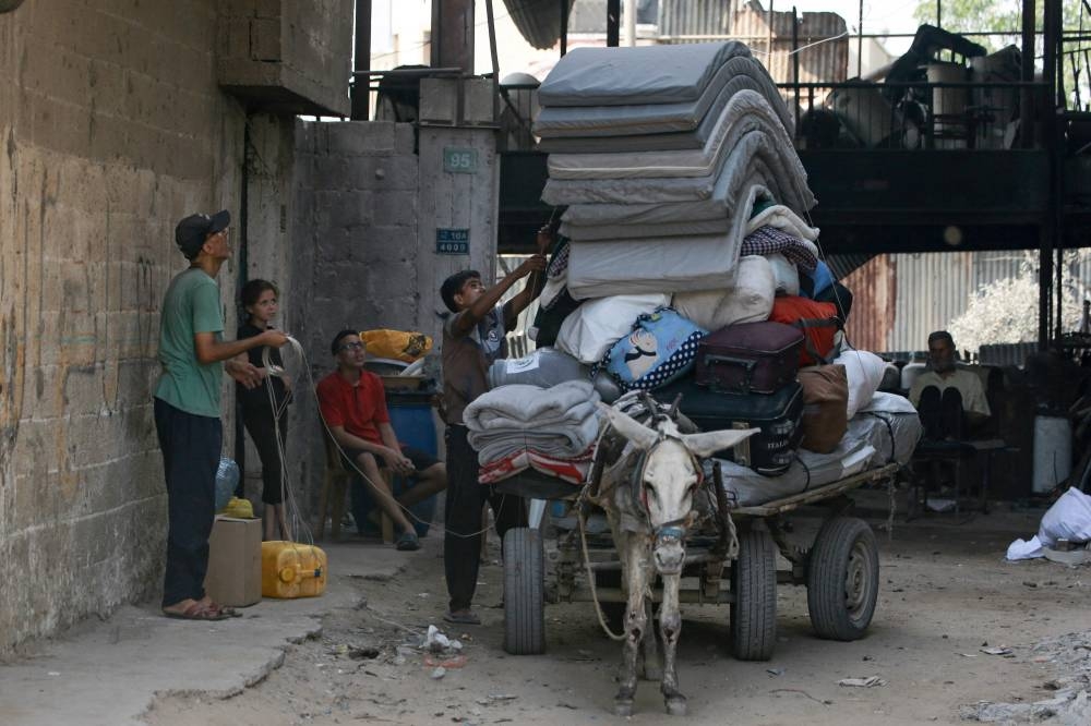 Palestinians load their belongings on a donkey-pulled cart as they prepare to flee the Abu Iskandar neighborhoods of northern Gaza City on August 22, 2025. (AFP)