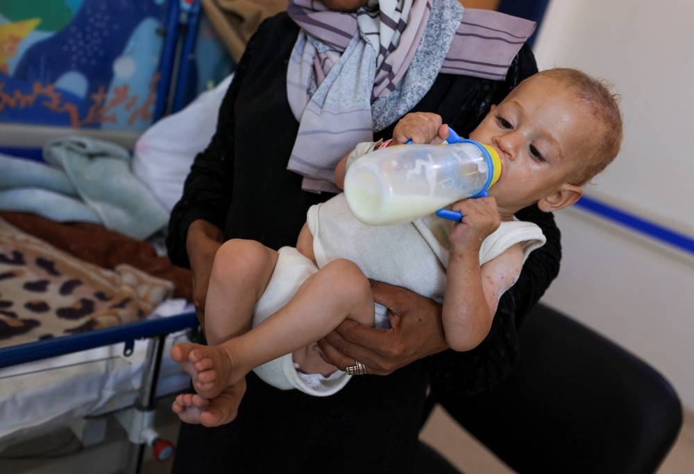 Aisha Wahdan, mother of 8-month-old Hatem, who is being treated for malnutrition, feeds him milk at Al-Rantisi Hospital, amid severe shortages of infant formula, in Gaza City, August 7. REUTERS