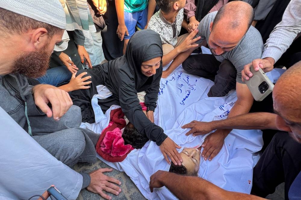 Mourners gather around the body of a Palestinian, during the funeral of Palestinians killed in an Israeli strike on a tent camp, at Nasser hospital in Khan Younis, in the southern Gaza Strip August 23, 2025. REUTERS