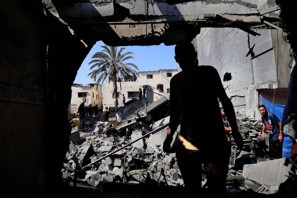 Palestinians inspect the site of an Israeli strike on a house in Deir Al-Balah, in the central Gaza Strip August 23, 2025. REUTERS