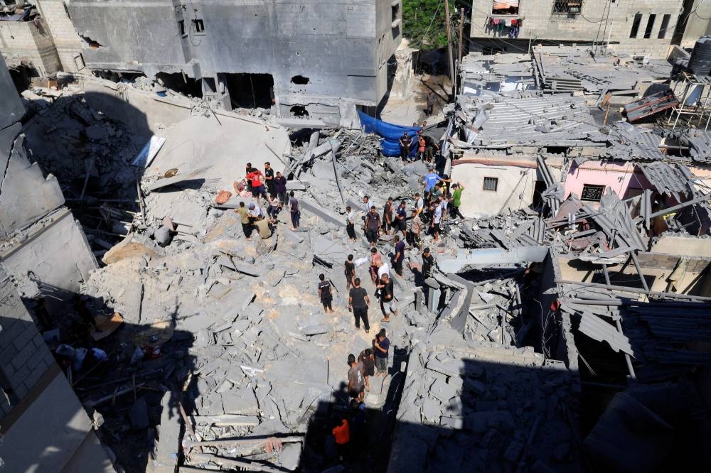 Palestinians inspect the site of an Israeli strike on a house in Deir Al-Balah, in the central Gaza Strip August 23, 2025. REUTERS