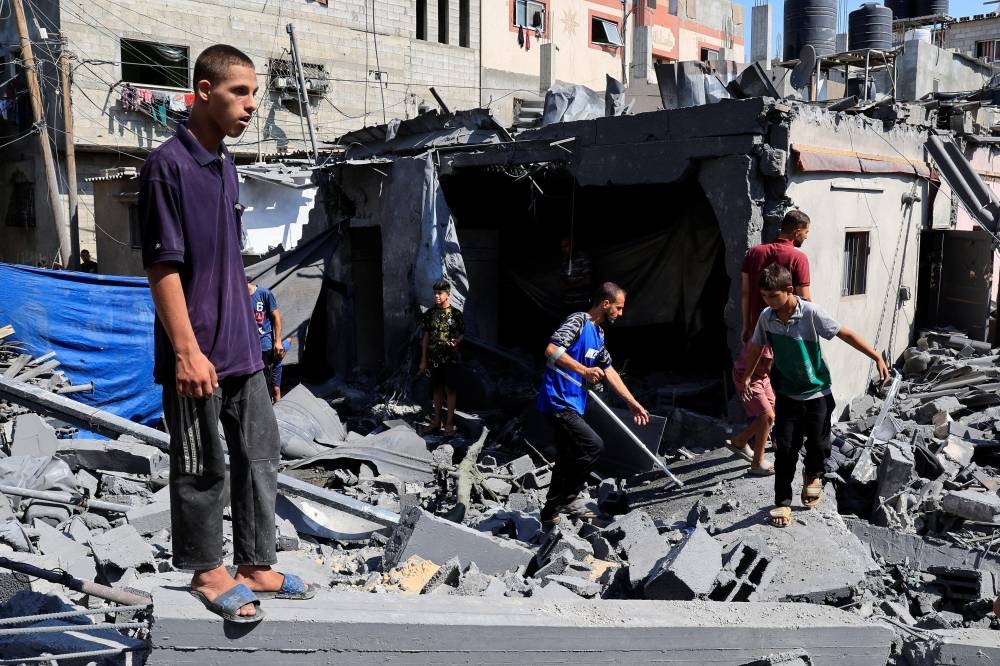 Palestinians inspect the site of an Israeli strike on a house in Deir Al-Balah, in the central Gaza Strip August 23, 2025. REUTERS