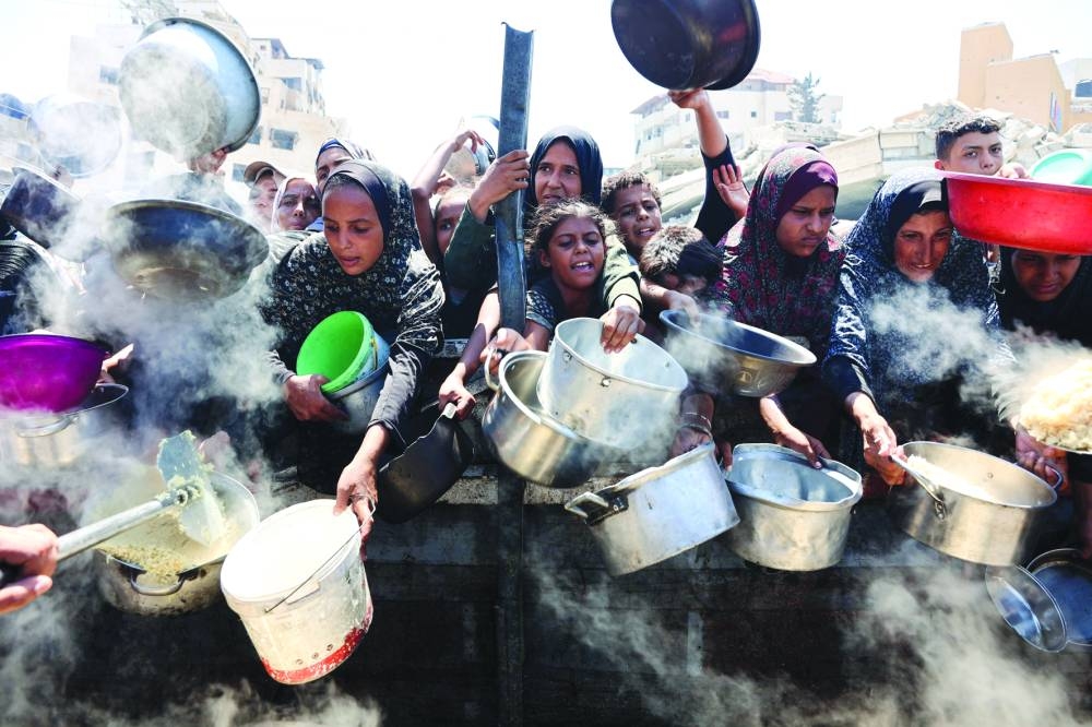 Palestinian women and girls elbow their way to receive cooked rice from charity kitchen in Gaza City,Saturday 