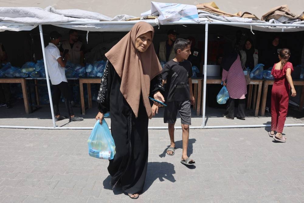 A displaced Palestinian woman walks away with a food ration get received from the Gaza Soup Kitchen in the Sheikh Radwan neighbourhood of Gaza City on Sunday. AFP