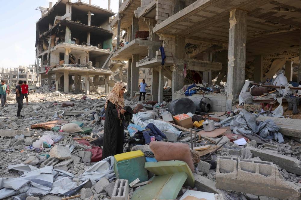Palestinians collect salvaged items following an explosion in the Saftawi neighborhood, west of Jabalia in the northern Gaza Strip on August 25, 2025, (AFP)