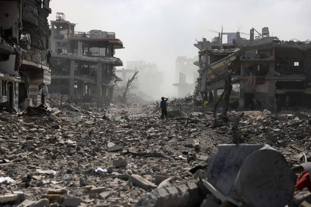 A Palestinian youth stands on a street strewn with rubble following an explosion in the Saftawi neighborhood, west of Jabalia in the northern Gaza Strip on August 25, 2025, (AFP)