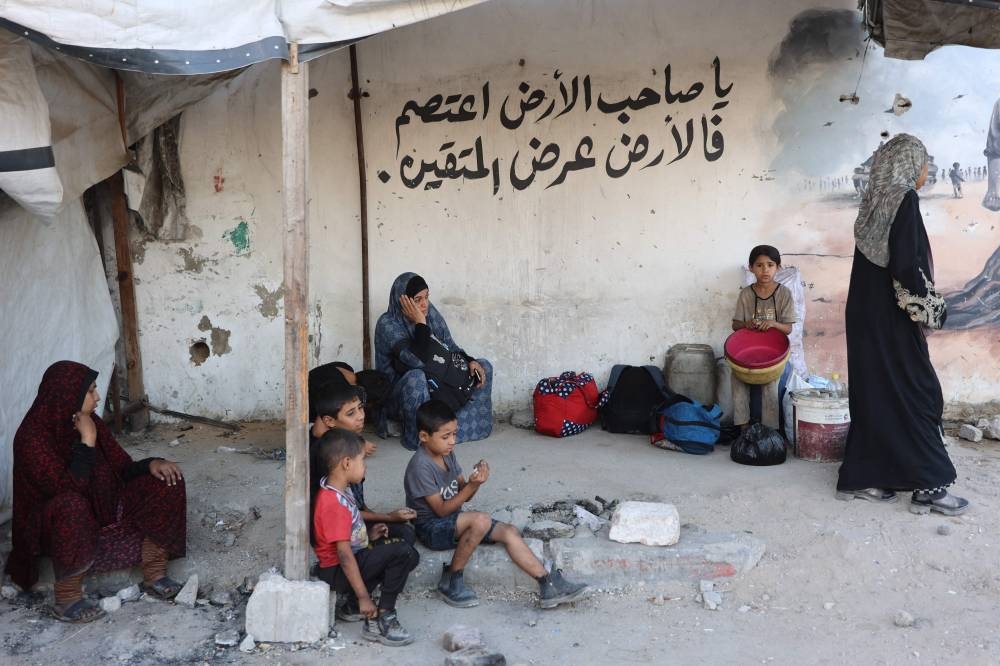 TOPSHOT - Palestinians rest on the side of a road as they flee their homes in Gaza City's Zeitoun neighbourhood on August 26, 2025. (AFP)