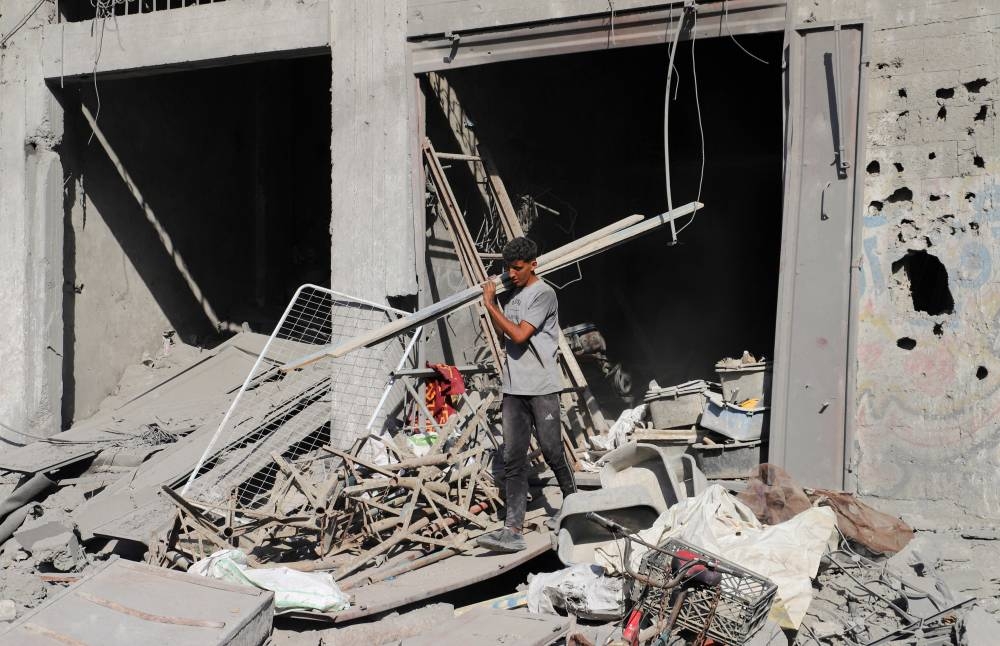 A Palestinian man walks at the site of an overnight Israeli strike on a house, in Gaza City, August 26, 2025. REUTERS