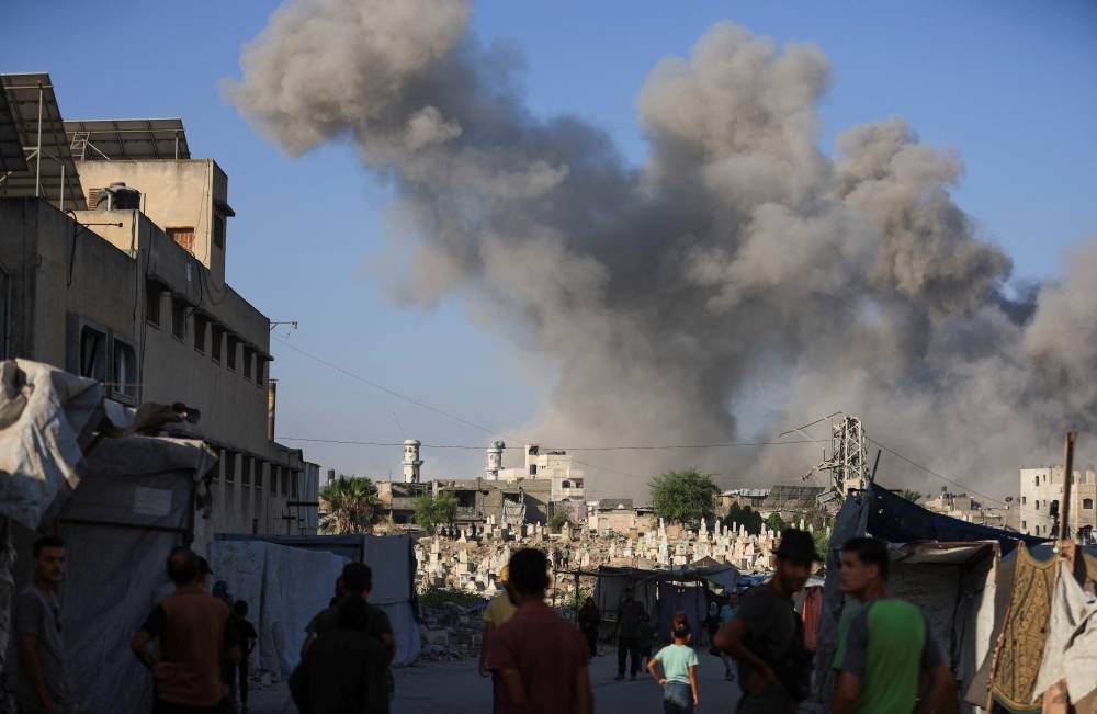 Palestinians look on as smoke rises following an explosion during an Israeli operation, in Gaza City, on Tuesday. REUTERS
