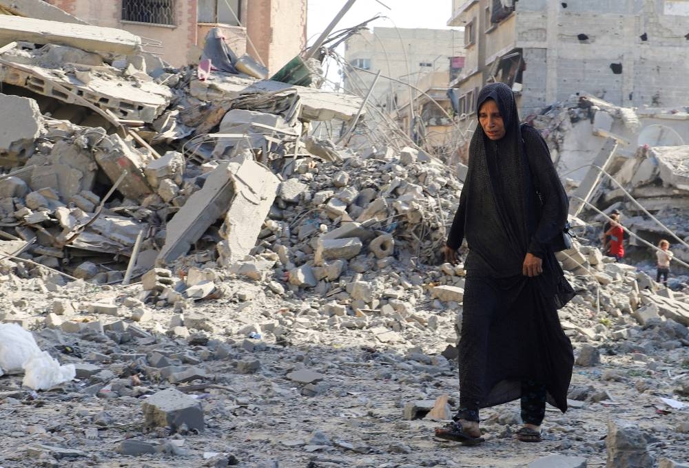 A woman walks at the site of an overnight Israeli strike on a house, in Gaza City, on Tuesday. REUTERS