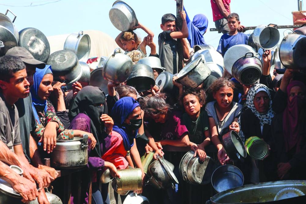 Palestinian women and children wait to receive food portions from a charity kitchen in Khan Yunis in the southern Gaza Strip,Wednesday.