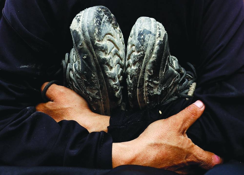Mother of Khaled al-Shinbari, a Palestinian teenager who was killed in Israeli fire while seeking aid in northern Gaza, according to medics, holds his shoes, during Khaled's funeral,at Al-Shifa Hospital in Gaza City Thursday. (Reuters)