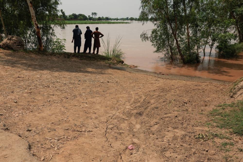 Residents are seen as cracks develop on the ground near a canal following monsoon rains and rising water levels, in Qadirabad village near the Chenab River in Pakistan’s Punjab province. – Reuters