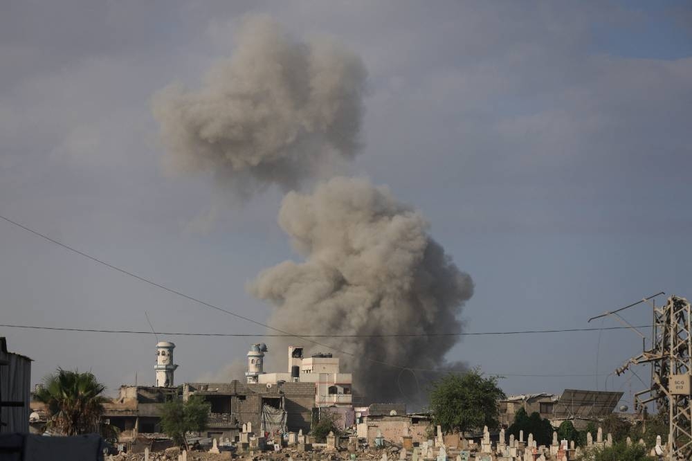 Tombstones are seen in the foreground as smoke rises following an explosion during an Israeli operation in Gaza City. REUTERS