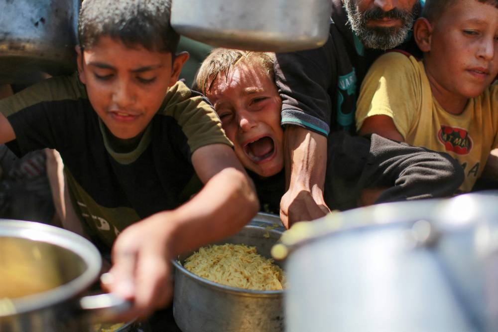 People try to get rice from a charity kitchen providing food for free in the west of Gaza City, on August 28, 2025. (AFP)