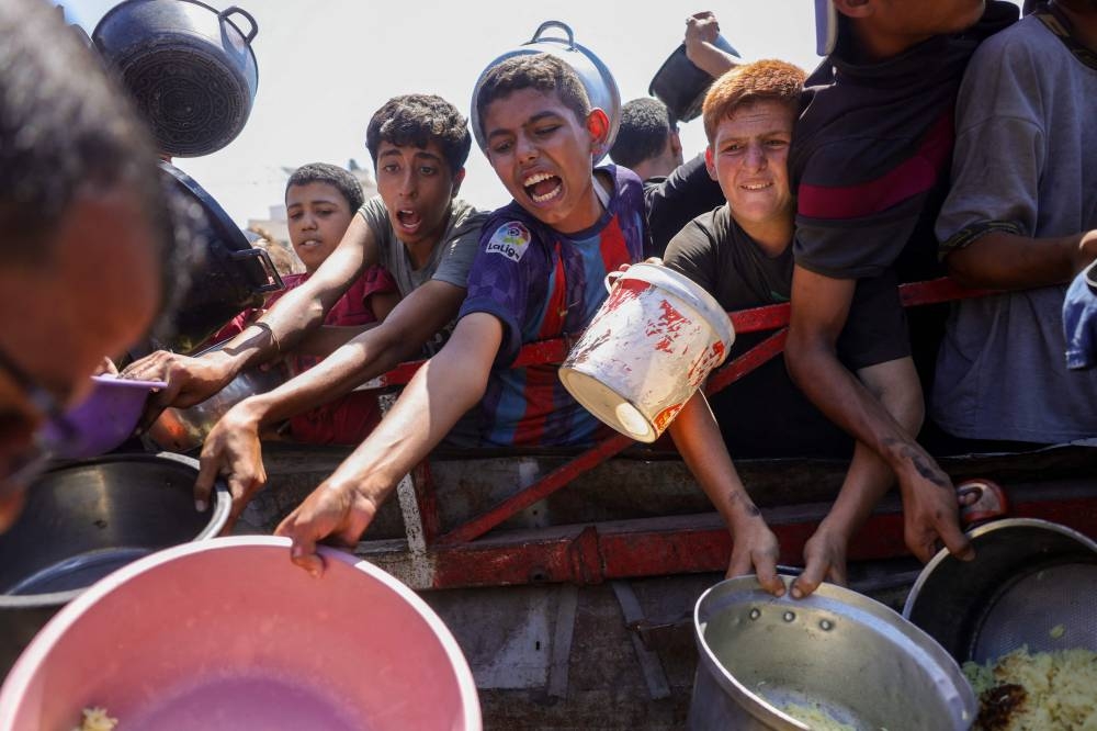 People try to get rice from a charity kitchen providing food for free in the west of Gaza City, on August 28, 2025. (AFP)