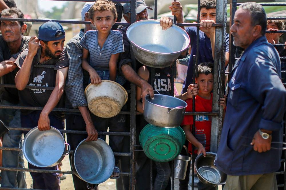 People wait as they try to get rice from a charity kitchen providing food for free in the west of Gaza City, on August 28, 2025. (AFP)