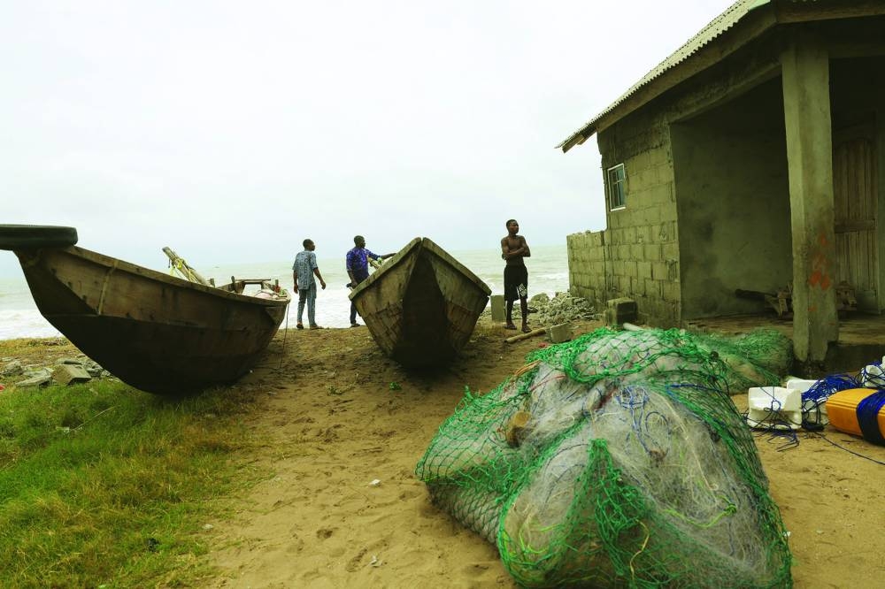 Fishermen react beside their home, which is on the verge of being swept away by ocean surges in Apakin, Nigeria.