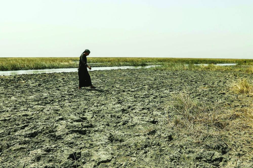 A farmer walks on dry patches exposed by the retreating water in the drought-striken Chibayish marshes in Iraq's southern Dhi Qar province.