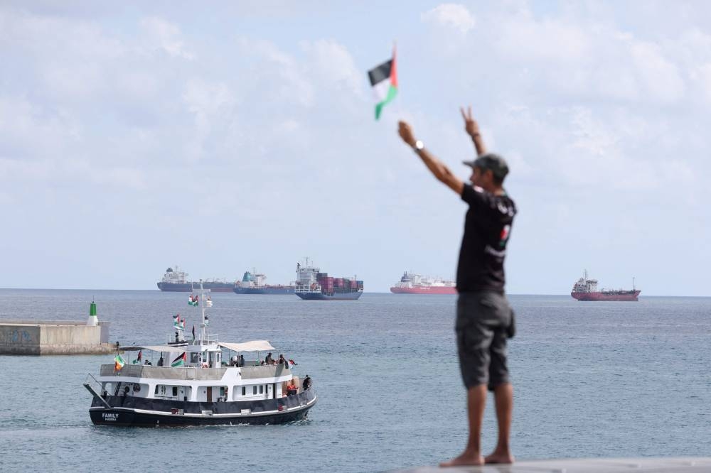 An activist waves the Palestinian flag as a boat carrying Swedish climate activist Greta Thunberg and activists, part of a civilian flotilla aiming at breaking the Israeli blockade of the Gaza Strip, leaves the port of Barcelona, on Sunday. AFP