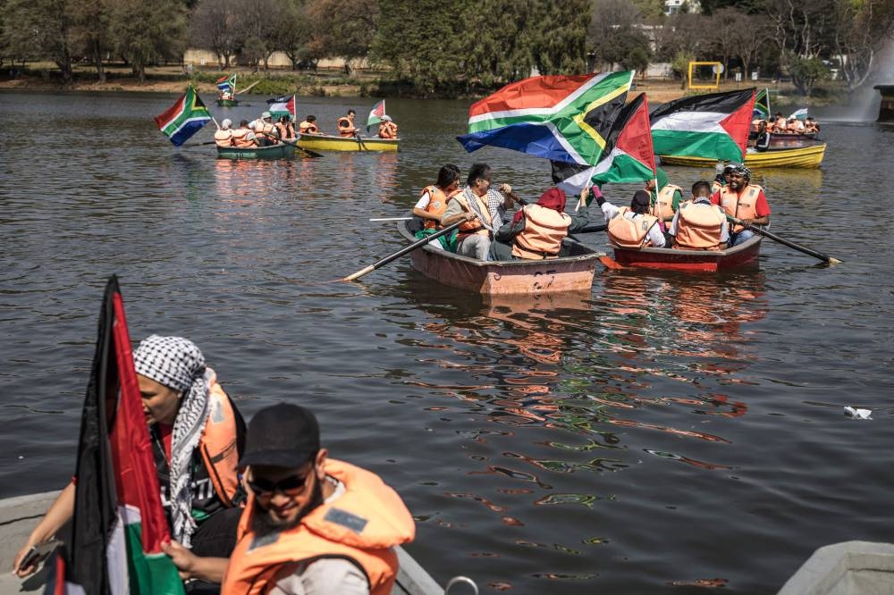Activists wave South African and Palestinian flags as they prepare to row on an artificial lake in Johannesburg, on Sunday. REUTERS