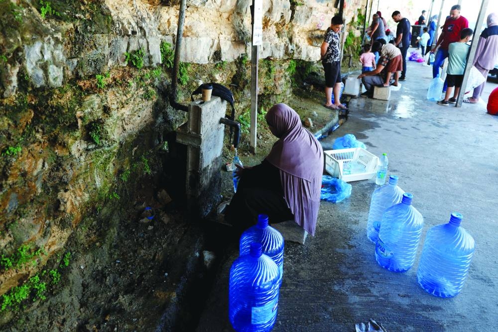 A Palestinian woman fills water containers from a public water point, in Ramallah in the occupied West Bank.