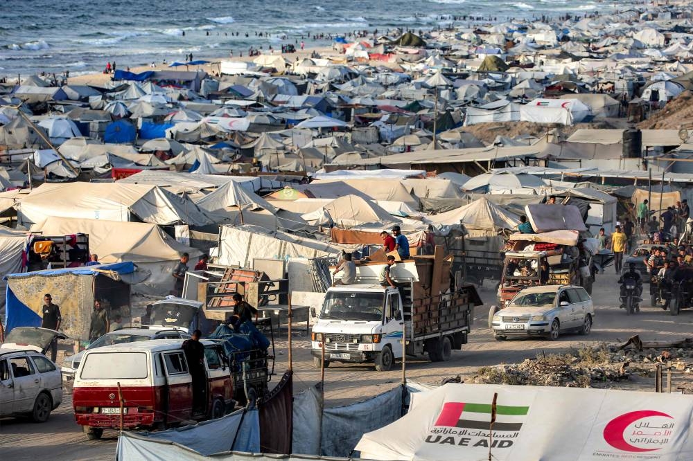 Vehicles move past people's tents erected along the waterfront in Gaza City as people evacuate southbound on Tuesday. AFP