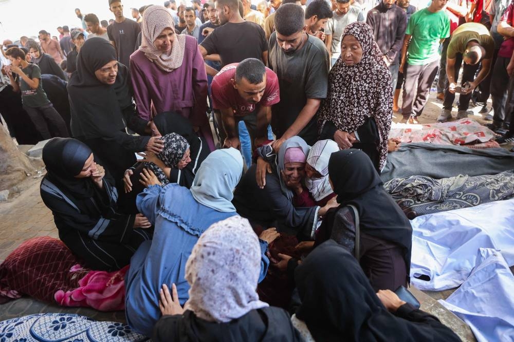 Palestinians mourn by the shrouded bodies of relatives killed in Israeli strikes on Gaza City at dawn, at the Al-Shifa hospital on Tuesday. AFP