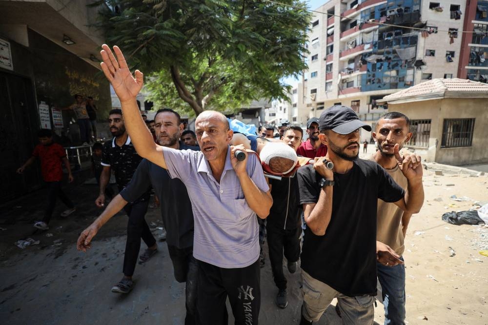 Palestinians carry the body of a man killed in an Israeli strike on a tent, according to medics, outside Al-Shifa Hospital in Gaza City, September 4, 2025. REUTERS