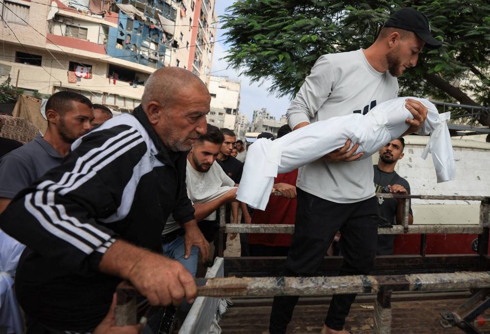 A mourner carries the covered body of a child during the funeral of Palestinians who were killed by Israeli fire while trying to receive aid on Wednesday and others who were killed in overnight strikes, according to medics, at Al-Shifa Hospital in Gaza City, September 4, 2025. REUTERS