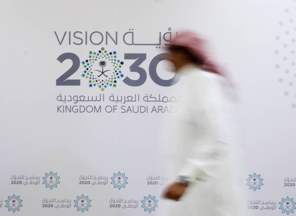 A Saudi man walks past the logo of Vision 2030 in Jeddah. Saudi Arabia sees foreign investment as key to training its young population, developing new industries and easing the government’s spending burden under the Vision 2030 economic transformation programme. FDI inflows amounted to $6.4bn in the first quarter of this year, according to preliminary data.