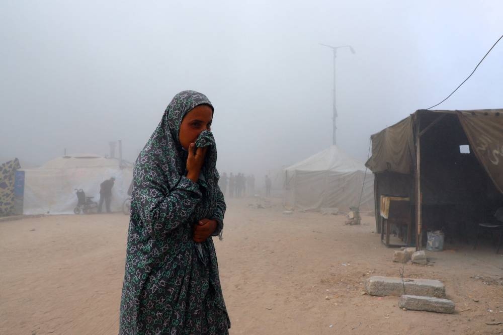 A Palestinian woman covers her mouth amid smoke after a building was hit by an Israeli air strike, in Gaza City, September 5, 2025. REUTERS