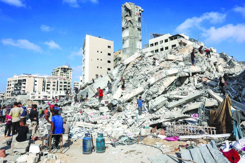 People search for salvage at the mound of rubble at the site of the collapsed Sussi Tower, which was destroyed earlier by Israeli bombardment, in Gaza City Saturday.