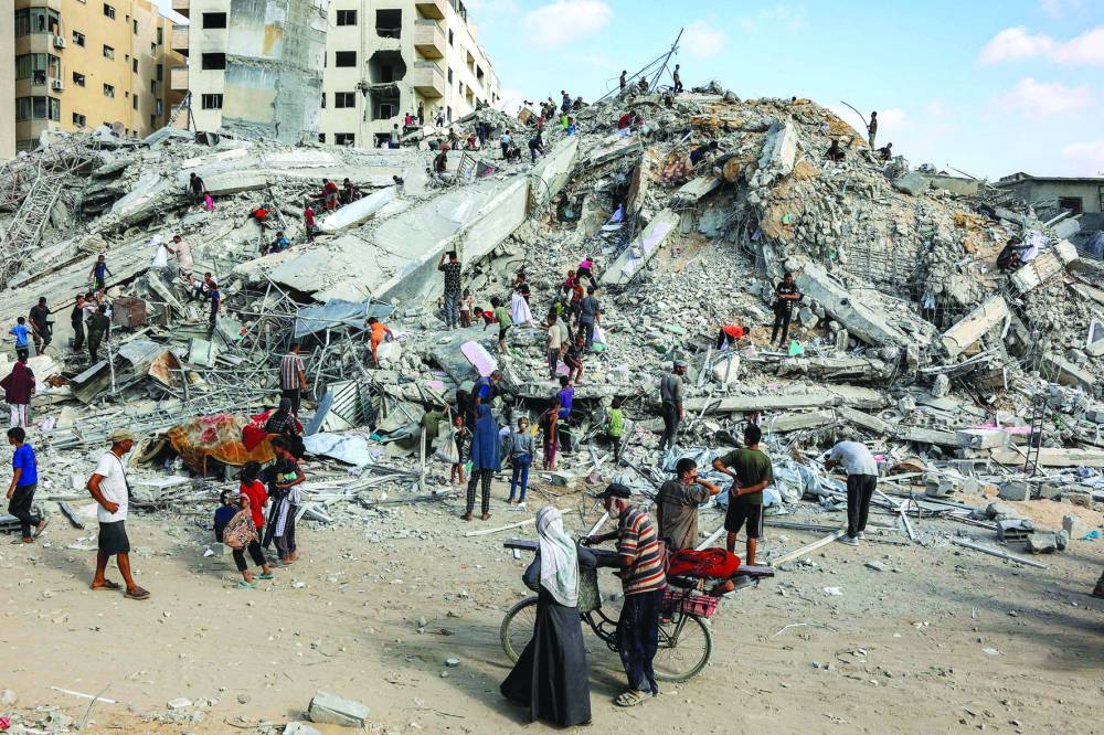 People search for salvage at the mound of rubble at the site of the collapsed Sussi Tower, which was destroyed earlier by Israeli bombardment, in Gaza City Saturday.