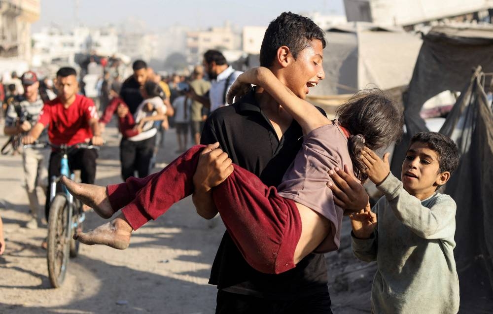 A Palestinian carries a wounded girl in the aftermath of an Israeli strike in Gaza City, Sunday.