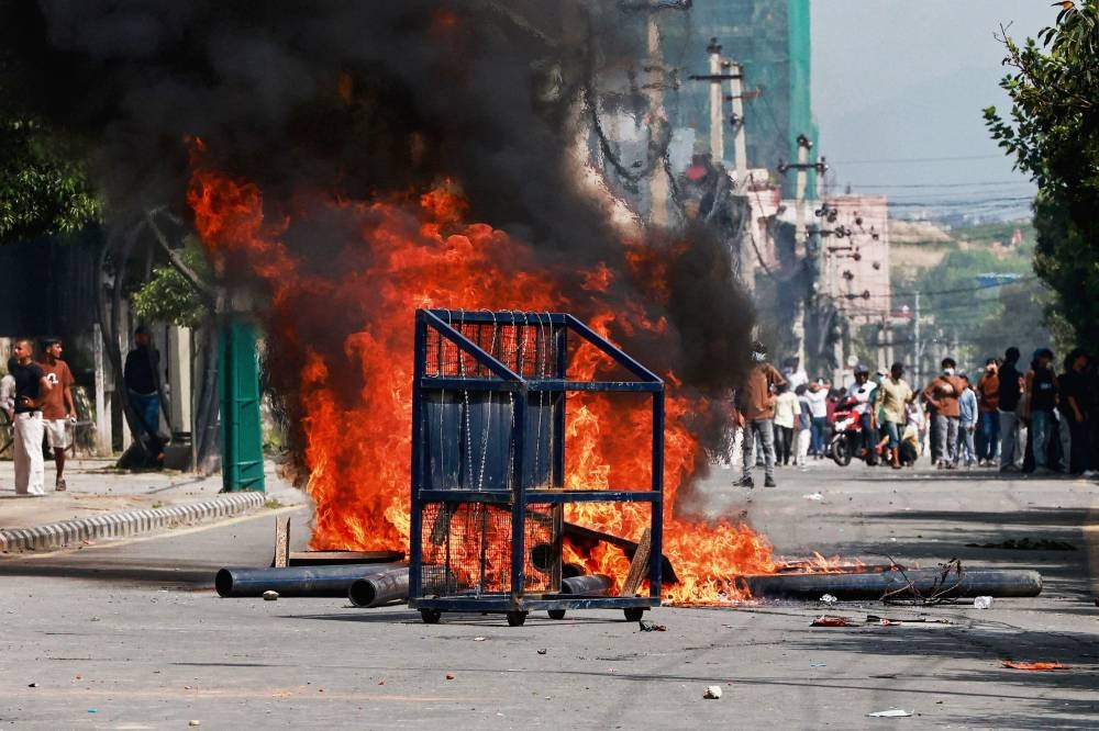 A police barricade is pictured in front of a fire set alight by demonstrators during a protest outside the Parliament in Kathmandu on Monday, condemning social media prohibitions and corruption by the government. AFP