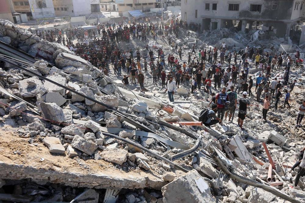 Palestinians check the rubble of  al-Ruya Tower in Gaza City following Israeli army bombardment, Monday.