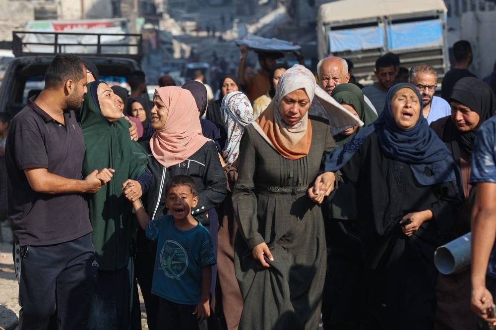Palestinians cry as they walk outside al-Shifa hospital in Gaza City where casualties of early Israeli strikes were transported, on Monday. AFP