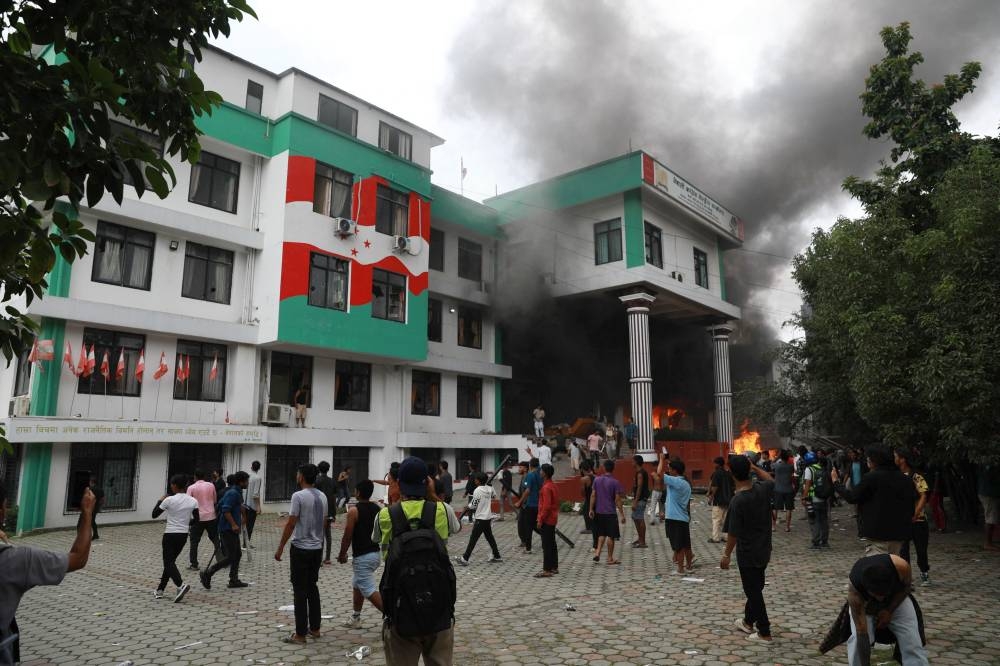 Demonstrators gather outside the burning Nepali Congress Party office during a protest to condemn the police's deadly crackdown on demonstrators in Kathmandu on September 9, 2025 (AFP)